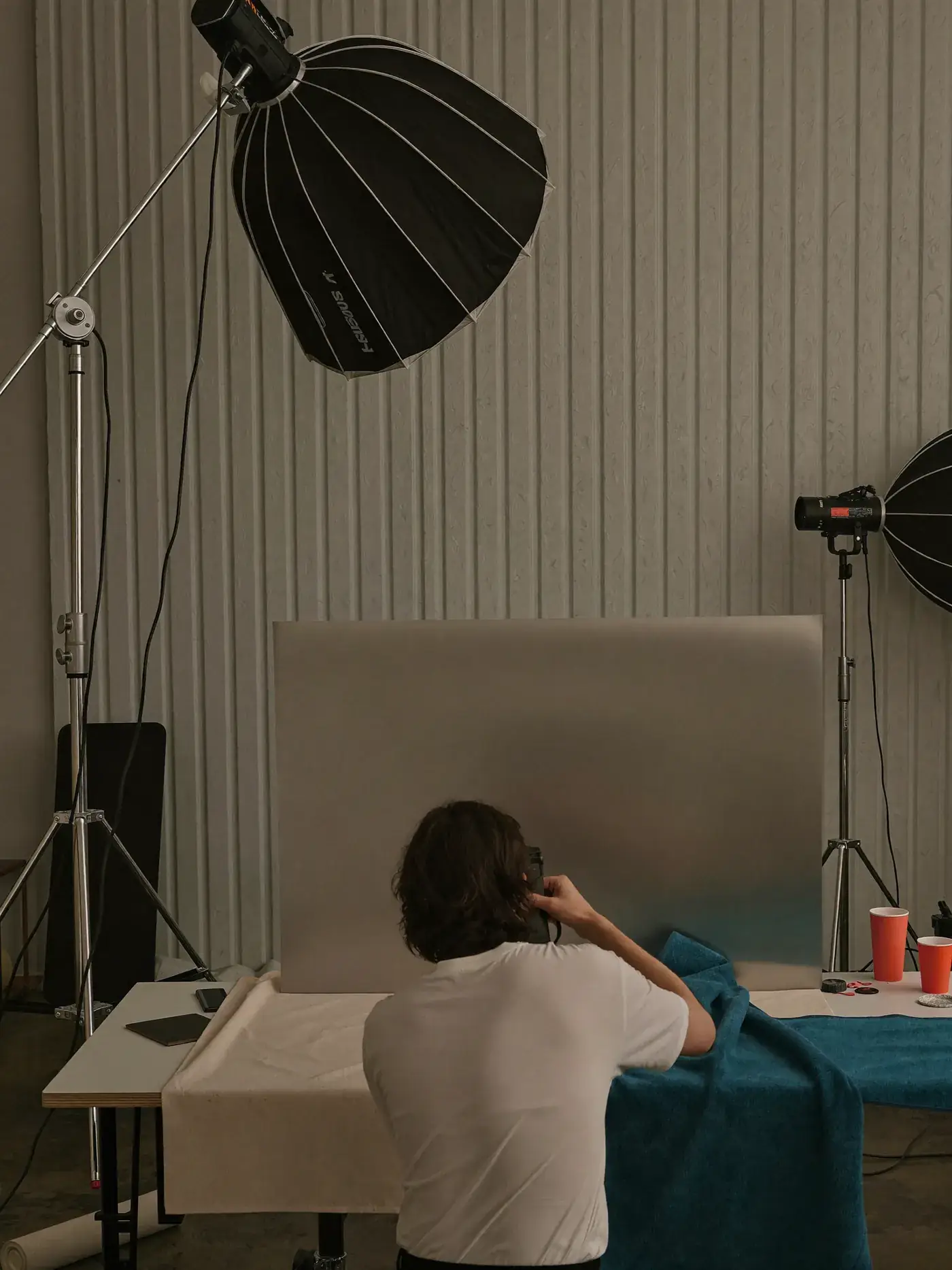 A photographer sets up a product shoot in a studio with softboxes and a paper sweep. Sample image created by Quiamo, a brand, marketing and media agency from India.
