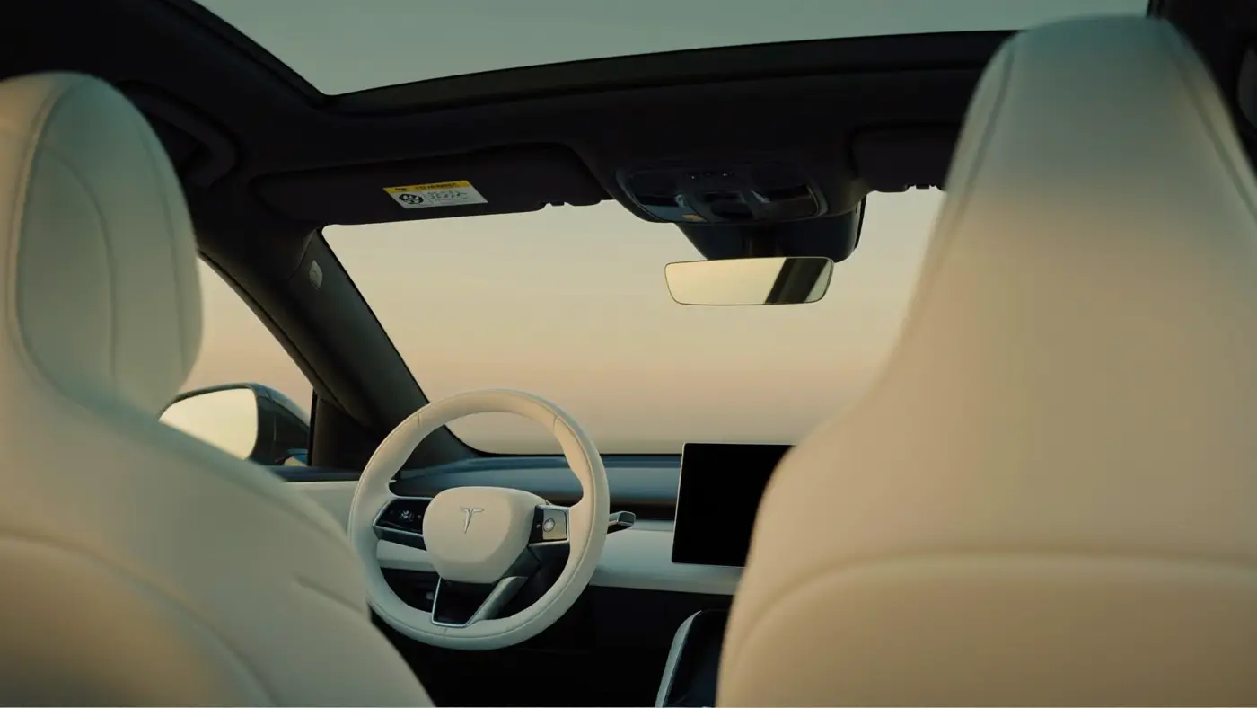 The calm interior of a minimalist electric car with cream seats and a panoramic glass roof at dusk.