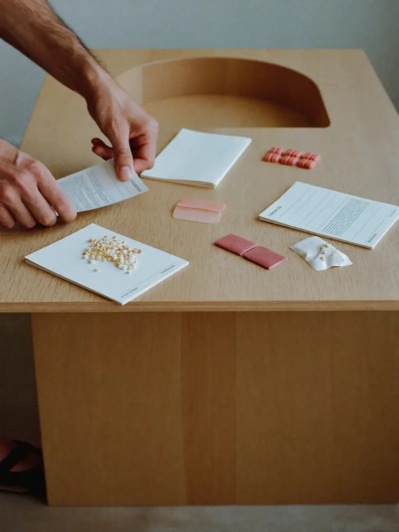 Hands arranging blank index cards and material samples into groups on a pale oak table, illustrating STP marketing.