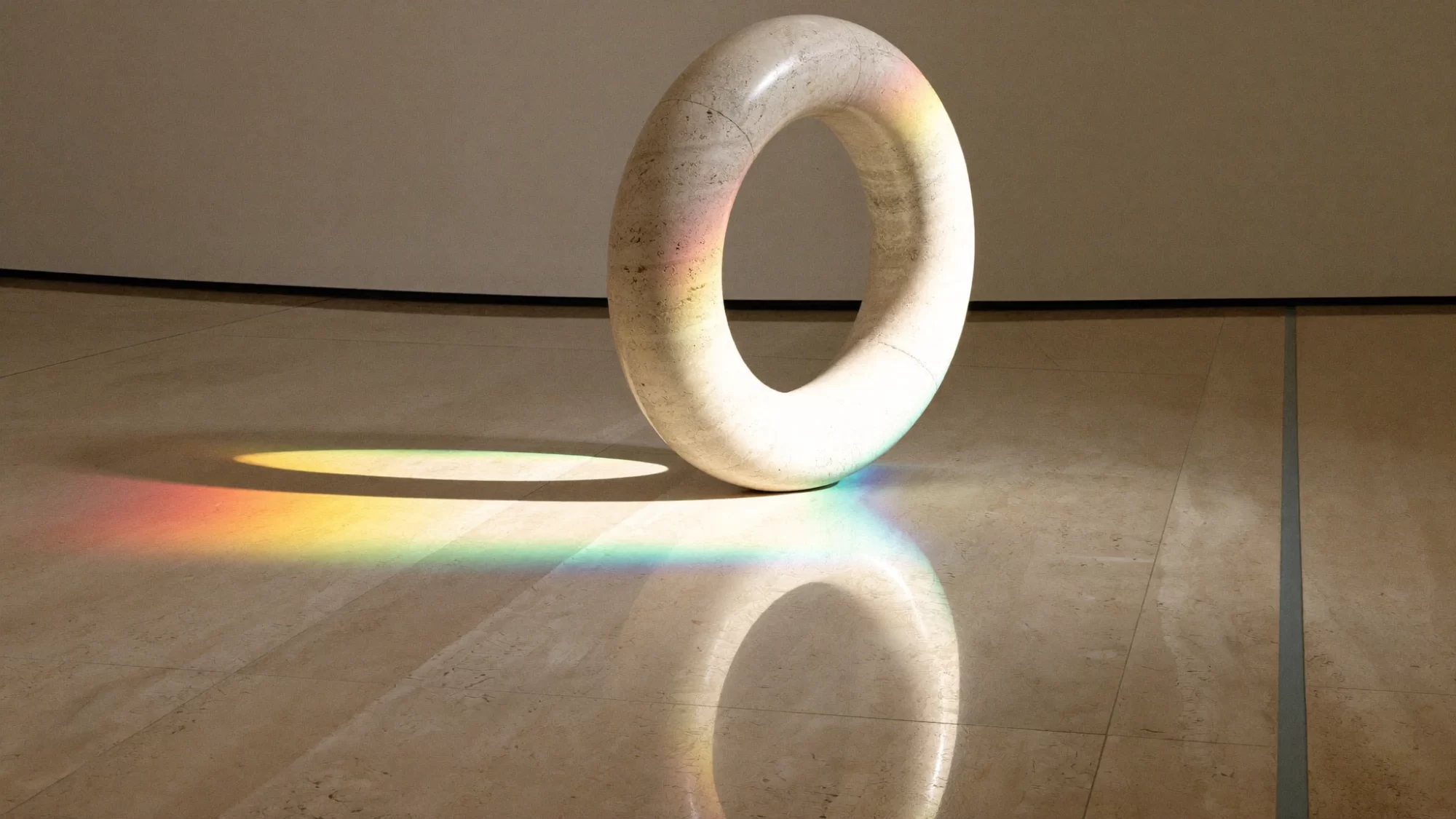 A travertine ring stands on an ivory floor while a beam through a prism throws a soft rainbow across it. Sample image created by Quiamo, a brand, marketing and media agency from India.