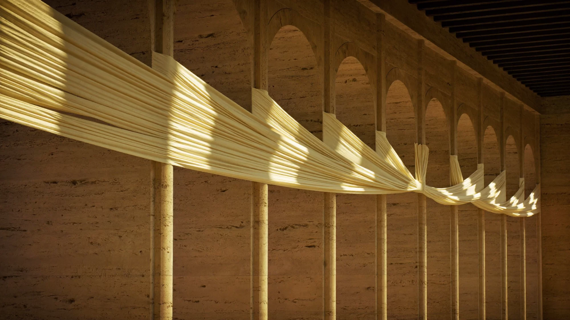 A woman in a long ivory coat stands in sunlit stone arches as a sheet of ivory silk drifts through the light. Sample image created by Quiamo, a brand, marketing and media agency from India.