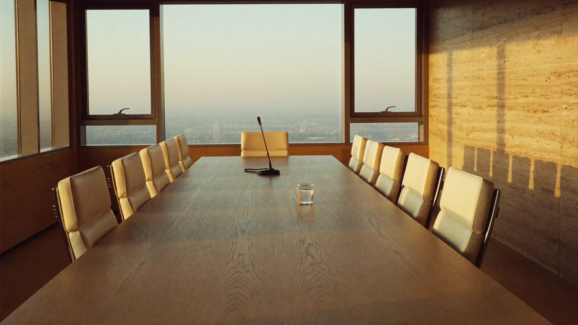 An empty boardroom at golden hour with a single conference microphone, corporate communications. Sample image created by Quiamo, a brand, marketing and media agency from India.