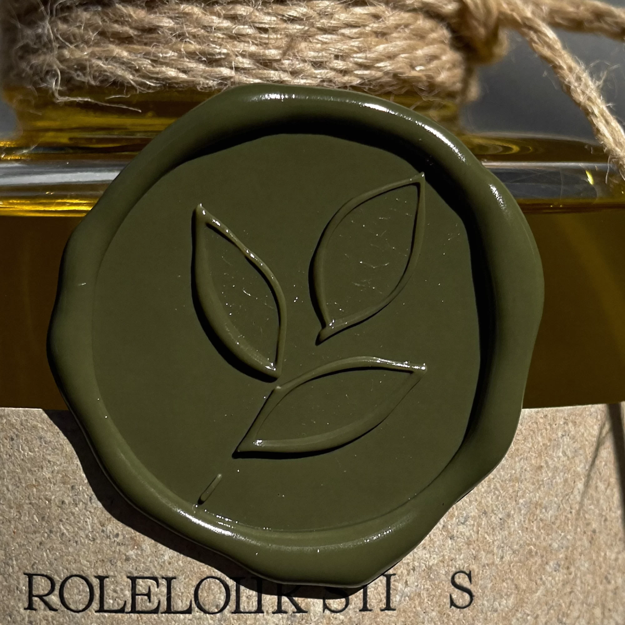 Stone Orchard Pantry concept: close-up of an olive green wax seal on the neck of a glass bottle. Sample image created by Quiamo, a brand, marketing and media agency from India.