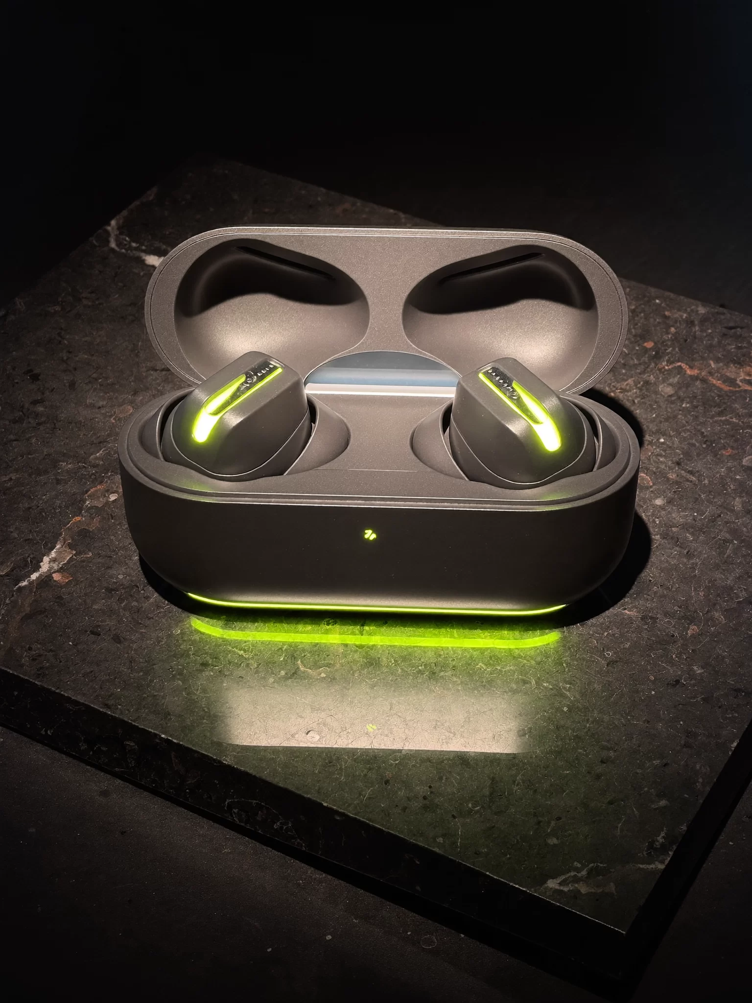 VOLTRA concept: a graphite wireless earbuds case with a lime light strip on dark stone. Sample image created by Quiamo, a brand, marketing and media agency from India.